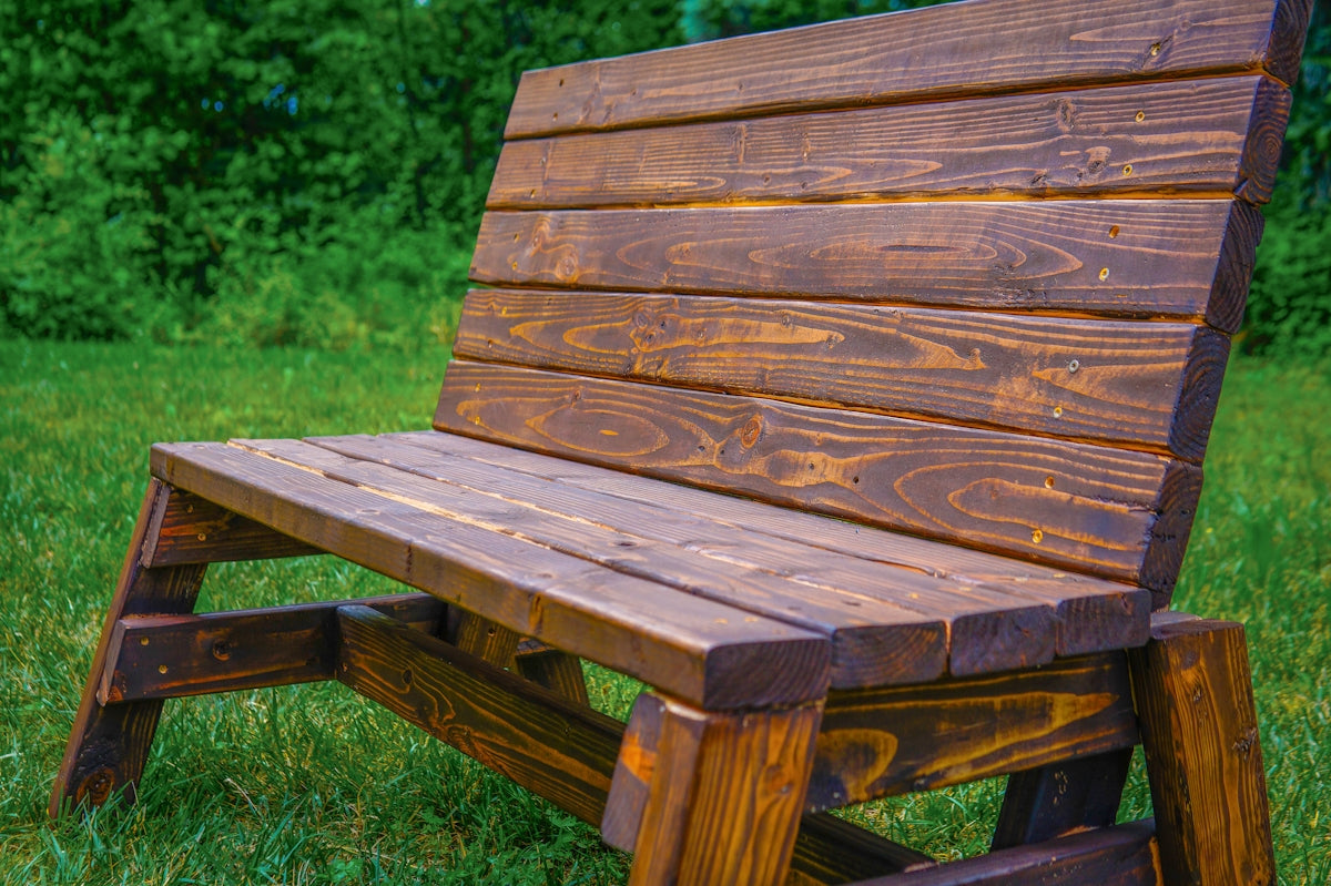 A rustic wooden bench sits on green grass outdoors.